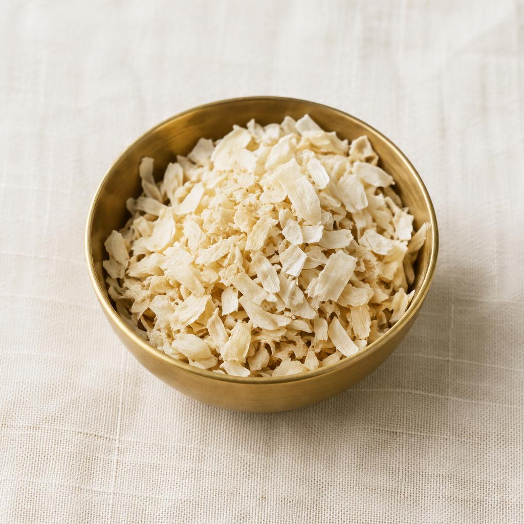 Dehydrated chopped onion pieces in a brass bowl on linen